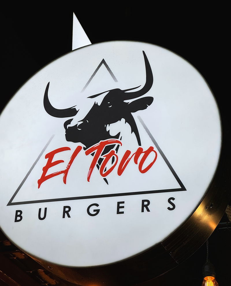 The round El Toro Burgers lightbox: a black bull’s head inside a triangle, “El Toro” in red script and “BURGERS” in spaced capitals