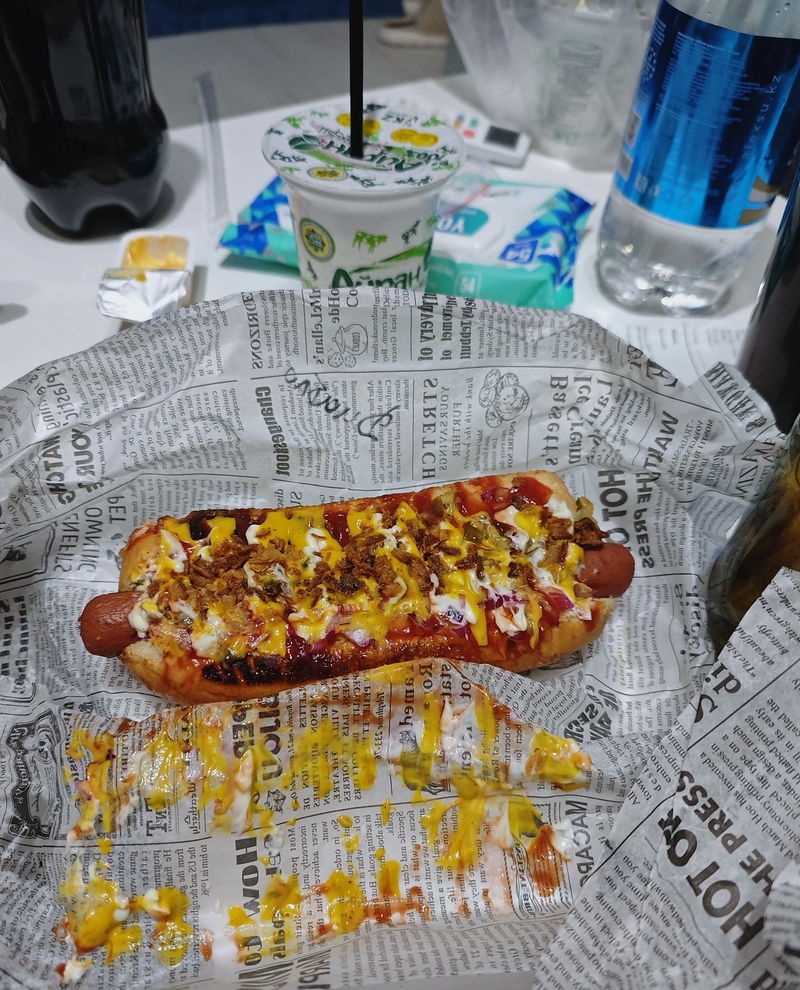A hot dog on newspaper-print wrap, seen from above