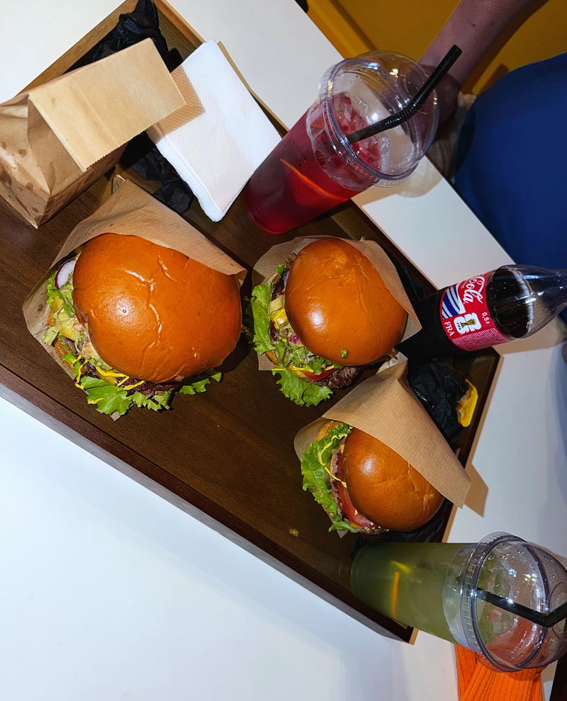 Four burgers and a cola on a wooden board