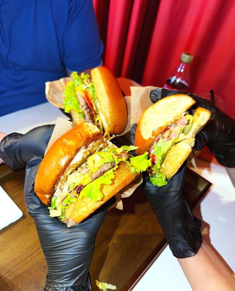 Guests raising their burgers against the red curtain in the room