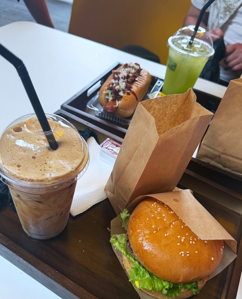 A burger and a hot dog with an iced coffee on the table